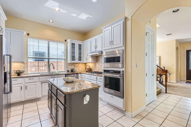 3824 Gaines Ct, Austin, TX 78735 - kitchen featuring stainless steel appliances, arched walkways, white cabinetry, light stone countertops, and light tile patterned flooring
