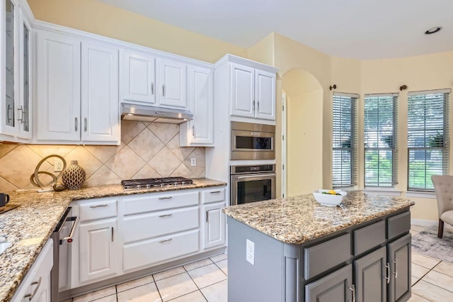 3824 Gaines Ct, Austin, TX 78735 - kitchen with appliances with stainless steel finishes, arched walkways, gray cabinetry, light tile patterned flooring, and white cabinetry