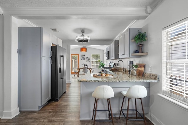1125 Christie Dr, Austin, TX 78721 - kitchen with appliances with stainless steel finishes, a peninsula, dark wood-style floors, open shelves, and light stone countertops