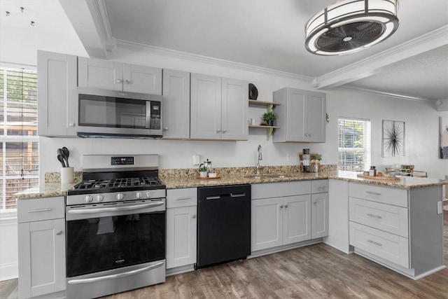 1125 Christie Dr, Austin, TX 78721 - kitchen featuring appliances with stainless steel finishes, open shelves, a peninsula, crown molding, and light wood-style floors