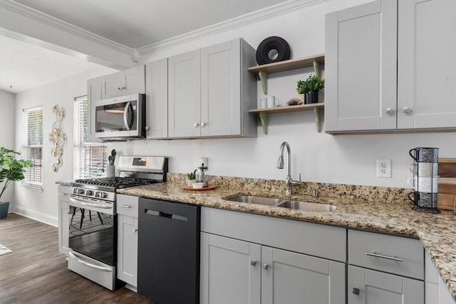 1125 Christie Dr, Austin, TX 78721 - kitchen featuring appliances with stainless steel finishes, a sink, ornamental molding, dark wood-style floors, and light stone countertops