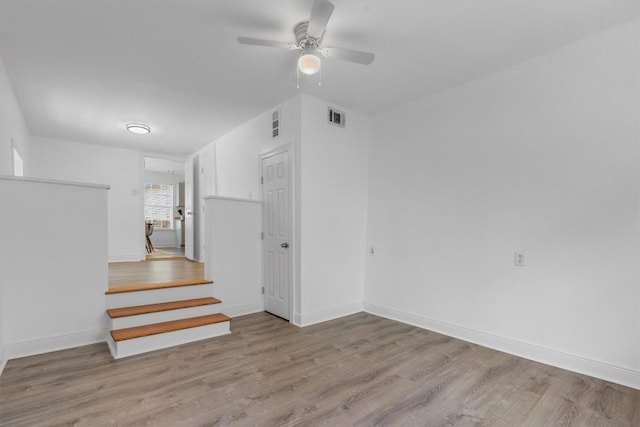 1125 Christie Dr, Austin, TX 78721 - unfurnished living room with a ceiling fan, wood finished floors, and stairway