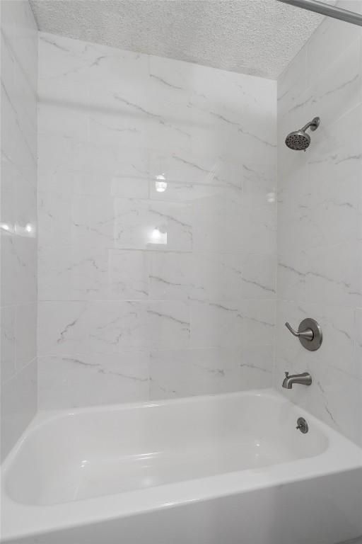 1125 Christie Dr, Austin, TX 78721 - bathroom with bathing tub / shower combination and a textured ceiling