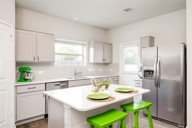 10701 Dimitrios Dr, Austin, TX 78747 - kitchen with stainless steel appliances, light countertops, tasteful backsplash, wood finished floors, and a center island