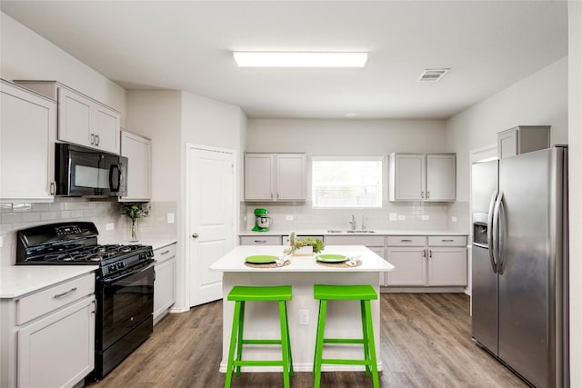 10701 Dimitrios Dr, Austin, TX 78747 - kitchen with black appliances, backsplash, light wood finished floors, and light countertops