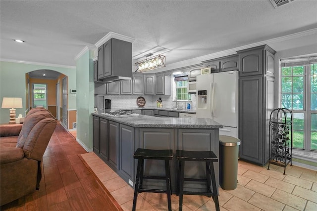 731 Verna Lee Blvd, Harker Heights, TX 76548 - kitchen with white refrigerator with ice dispenser, gray cabinets, stainless steel gas cooktop, arched walkways, and ornamental molding