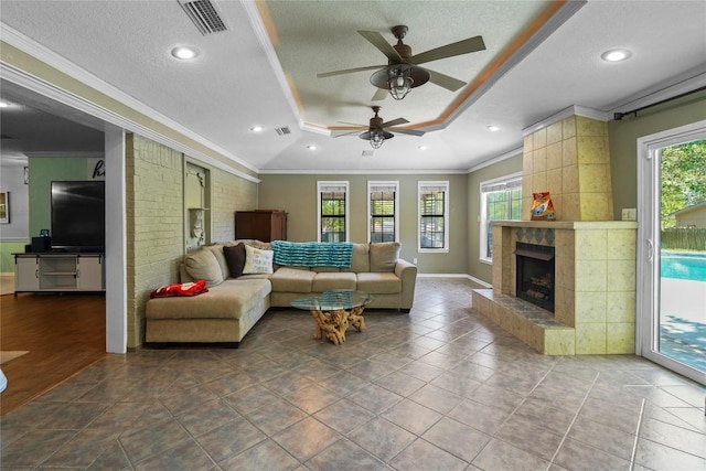 731 Verna Lee Blvd, Harker Heights, TX 76548 - living room with a tray ceiling, a textured ceiling, crown molding, ceiling fan, and a tile fireplace