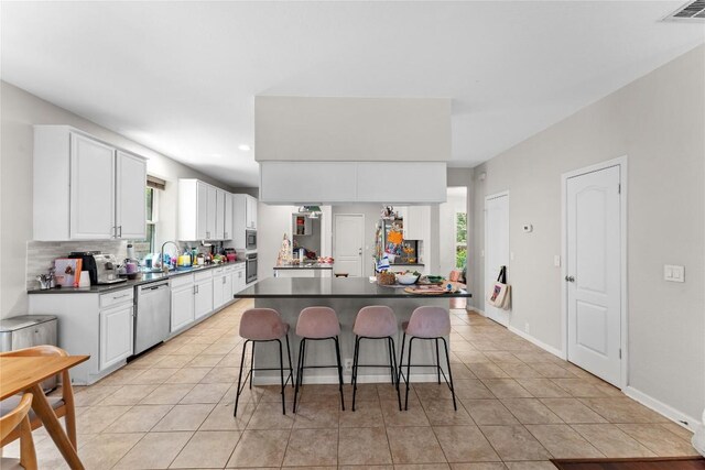 5357 Austral Loop, Austin, TX 78739 - kitchen featuring stainless steel appliances, dark countertops, a kitchen breakfast bar, white cabinetry, and light tile patterned flooring