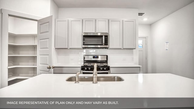 549 Osprey Dr, Leander, TX 78641 - kitchen with stainless steel appliances, decorative backsplash, light countertops, a sink, and recessed lighting