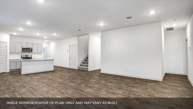 549 Osprey Dr, Leander, TX 78641 - kitchen featuring appliances with stainless steel finishes, recessed lighting, open floor plan, dark wood-type flooring, and a center island with sink