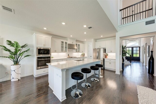 5028 Olimpico Way, Leander, TX 78641 - kitchen with stainless steel appliances, under cabinet range hood, dark wood-style flooring, an island with sink, and recessed lighting