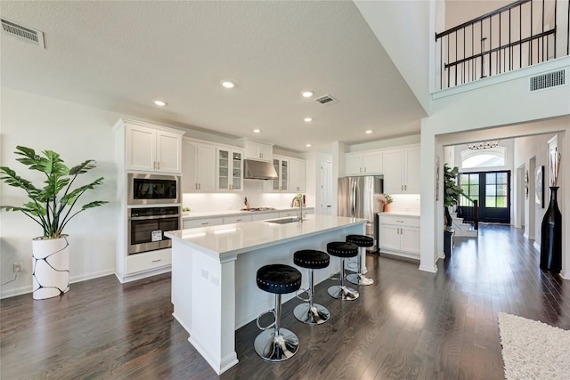 5028 Olimpico Way, Leander, TX 78641 - kitchen featuring stainless steel appliances, under cabinet range hood, dark wood finished floors, light countertops, and recessed lighting