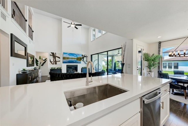 5028 Olimpico Way, Leander, TX 78641 - kitchen with a glass covered fireplace, open floor plan, dishwasher, light countertops, and white cabinets