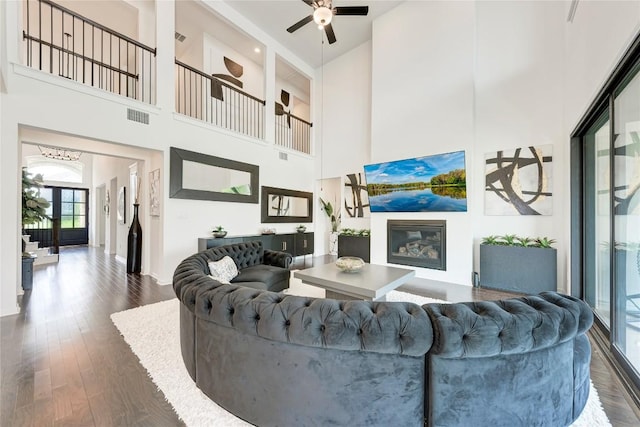 5028 Olimpico Way, Leander, TX 78641 - living area featuring a high ceiling, dark wood finished floors, a ceiling fan, a glass covered fireplace, and baseboards