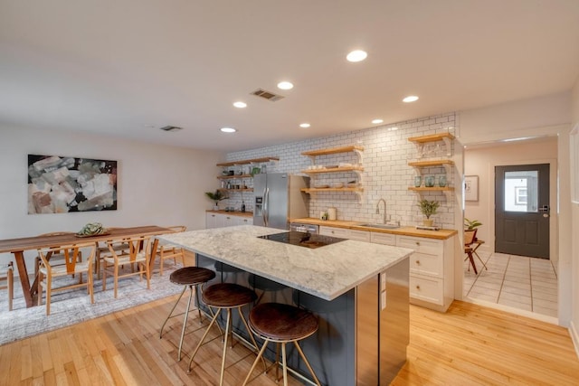 2010 Alguno Rd, Austin, TX 78757 - kitchen with open shelves, stainless steel refrigerator with ice dispenser, a center island, a kitchen bar, and tasteful backsplash