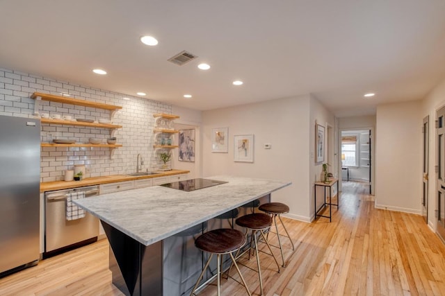 2010 Alguno Rd, Austin, TX 78757 - kitchen with stainless steel appliances, open shelves, a sink, a breakfast bar area, and a center island