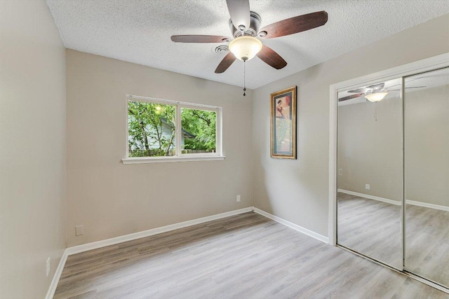 8711 Bridgeport Dr, Austin, TX 78758 - unfurnished bedroom featuring wood finished floors, a closet, a textured ceiling, and baseboards