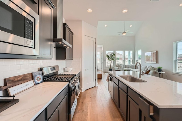 1531 N Red Bud Ln Unit 34, Round Rock, TX 78665 - kitchen featuring appliances with stainless steel finishes, light wood-style floors, wall chimney range hood, ceiling fan, and open floor plan