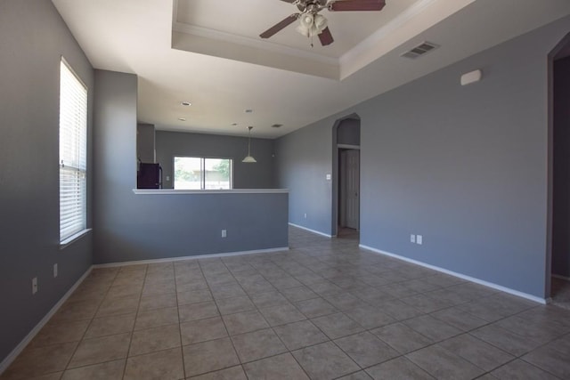564 Moonwalker Trl, Buda, TX 78610 - tiled spare room featuring arched walkways, ceiling fan, a tray ceiling, and baseboards