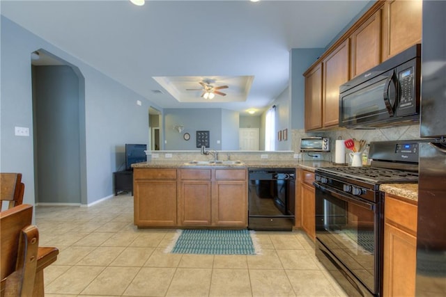 564 Moonwalker Trl, Buda, TX 78610 - kitchen featuring black appliances, a tray ceiling, a peninsula, a ceiling fan, and decorative backsplash