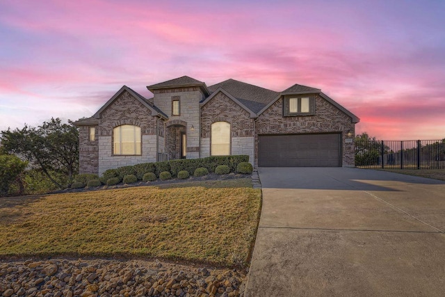 21808 Esmeralda Dr, Spicewood, TX 78669 - french country style house featuring driveway, stone siding, roof with shingles, and an attached garage