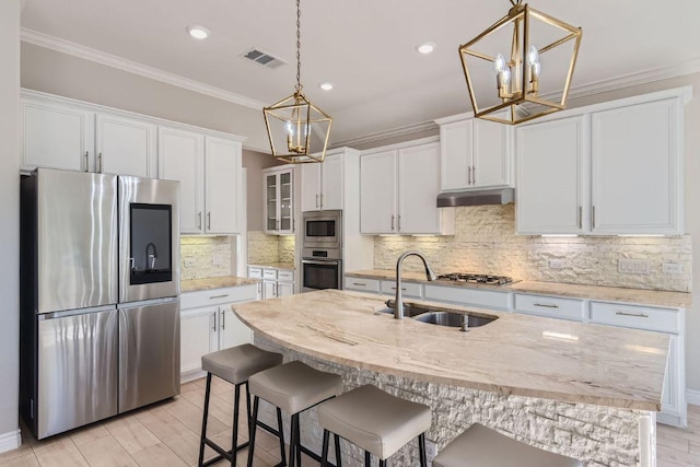21808 Esmeralda Dr, Spicewood, TX 78669 - kitchen featuring stainless steel appliances, a chandelier, a sink, crown molding, and white cabinets