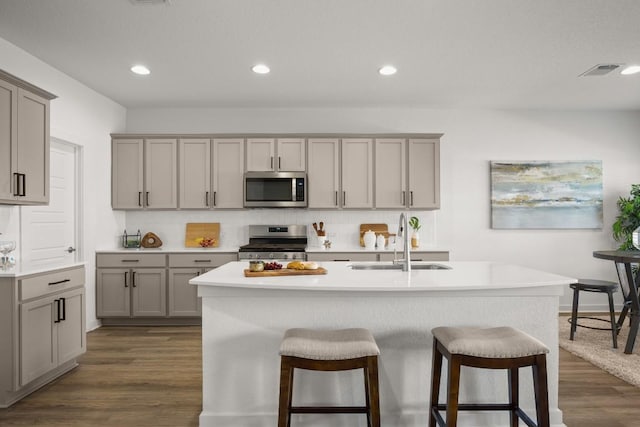 10208 Criswell Rd, Austin, TX 78754 - kitchen with appliances with stainless steel finishes, gray cabinetry, a sink, a breakfast bar, and light countertops