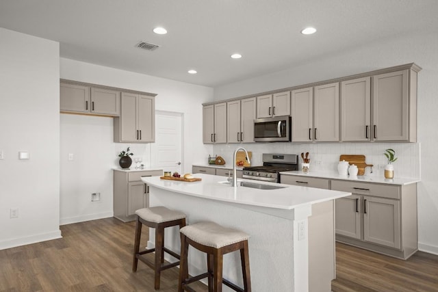 10208 Criswell Rd, Austin, TX 78754 - kitchen featuring appliances with stainless steel finishes, gray cabinetry, dark wood-style flooring, an island with sink, and recessed lighting