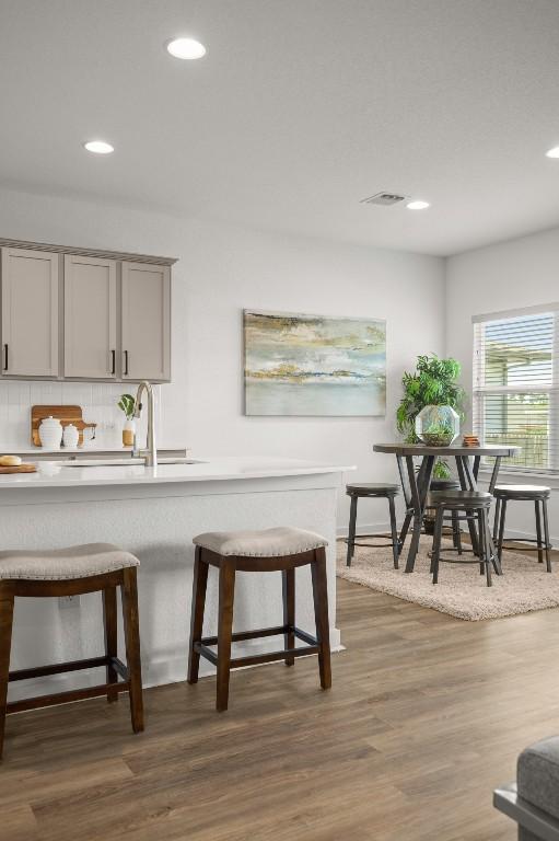10208 Criswell Rd, Austin, TX 78754 - kitchen featuring gray cabinetry, a breakfast bar area, recessed lighting, backsplash, and dark wood-style flooring