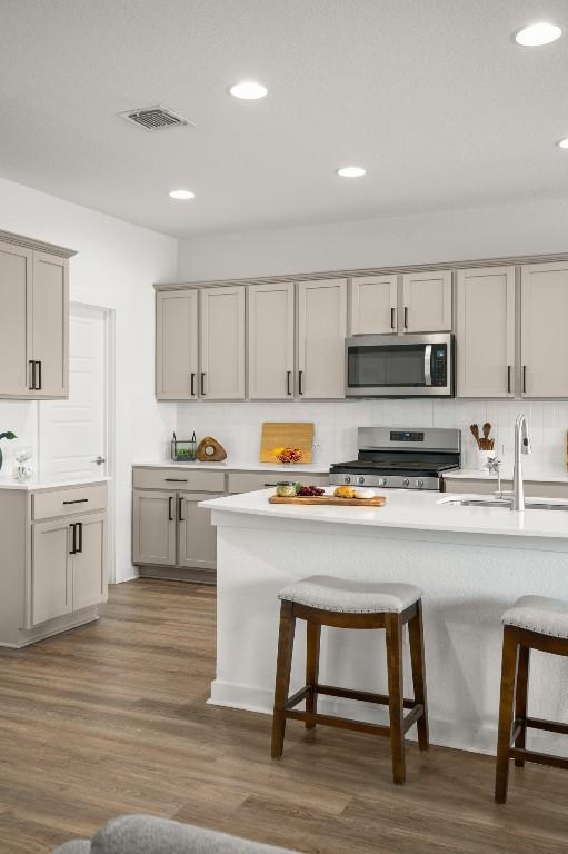 10208 Criswell Rd, Austin, TX 78754 - kitchen with appliances with stainless steel finishes, a kitchen bar, gray cabinets, light countertops, and recessed lighting
