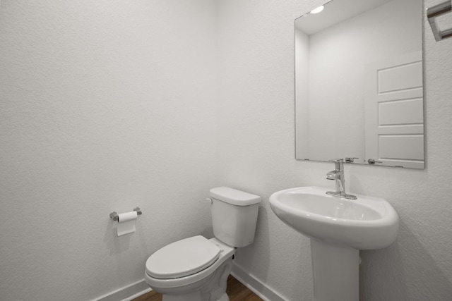 10208 Criswell Rd, Austin, TX 78754 - half bathroom featuring wood finished floors, toilet, baseboards, and a sink