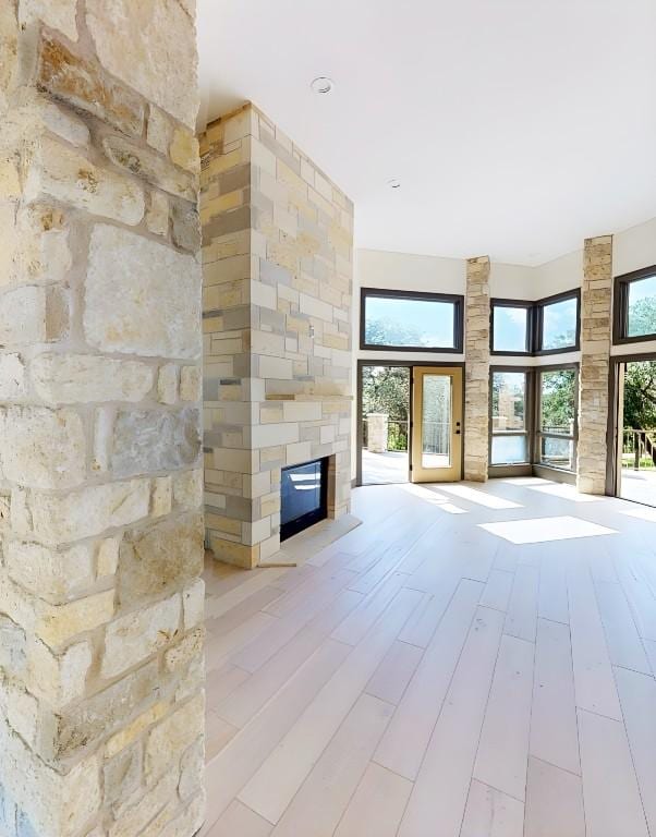 2700 Marina Shores Dr, Spicewood, TX 78669 - unfurnished living room featuring a stone fireplace, wood finished floors, and healthy amount of natural light
