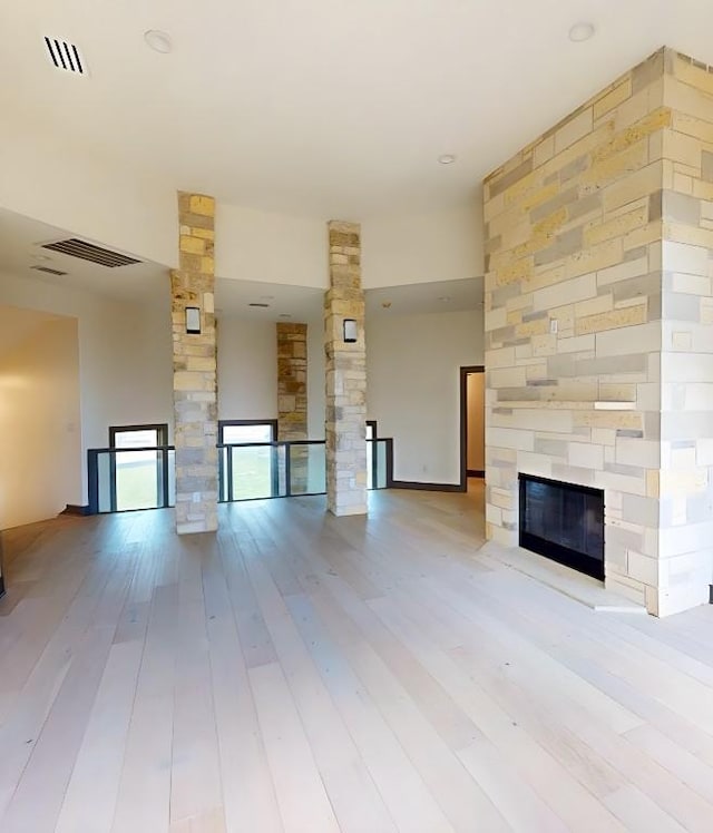 2700 Marina Shores Dr, Spicewood, TX 78669 - unfurnished living room featuring a stone fireplace and light wood-type flooring