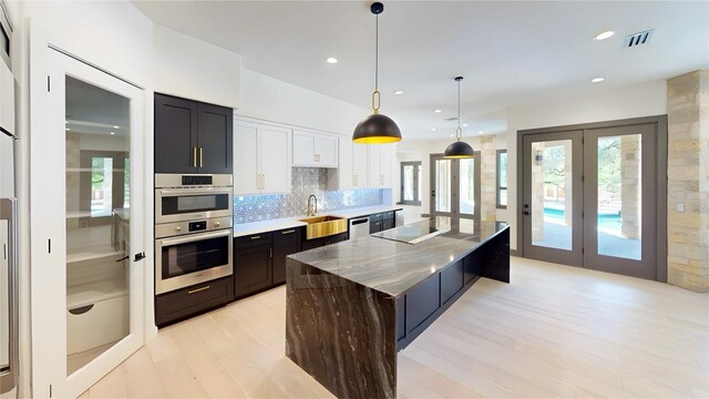 2700 Marina Shores Dr, Spicewood, TX 78669 - kitchen featuring a sink, light wood finished floors, appliances with stainless steel finishes, tasteful backsplash, and a large island