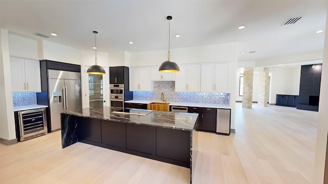 2700 Marina Shores Dr, Spicewood, TX 78669 - kitchen with beverage cooler, appliances with stainless steel finishes, a sink, backsplash, and dark stone countertops