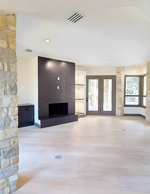 2700 Marina Shores Dr, Spicewood, TX 78669 - unfurnished living room with a large fireplace, french doors, light wood-type flooring, baseboards, and recessed lighting