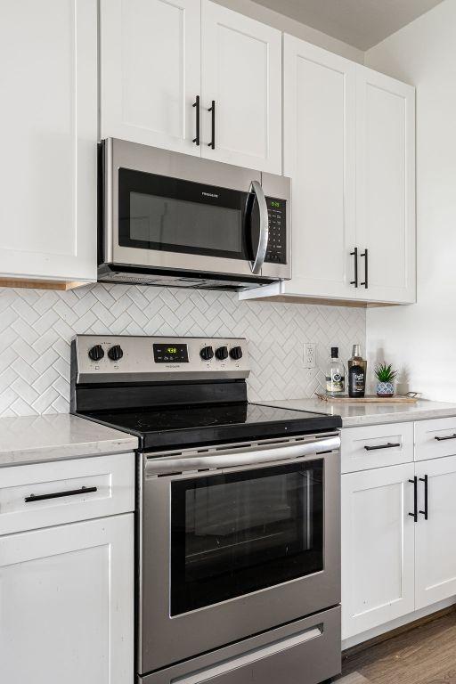148 Feather Way, Fredericksburg, TX 78624 - kitchen with appliances with stainless steel finishes, light countertops, white cabinetry, and decorative backsplash