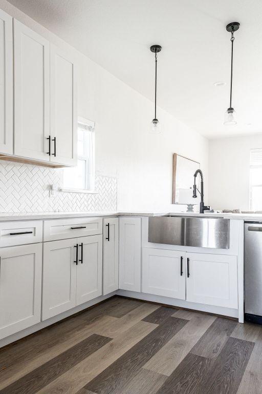 148 Feather Way, Fredericksburg, TX 78624 - kitchen featuring stainless steel dishwasher, white cabinetry, decorative backsplash, dark wood finished floors, and a sink