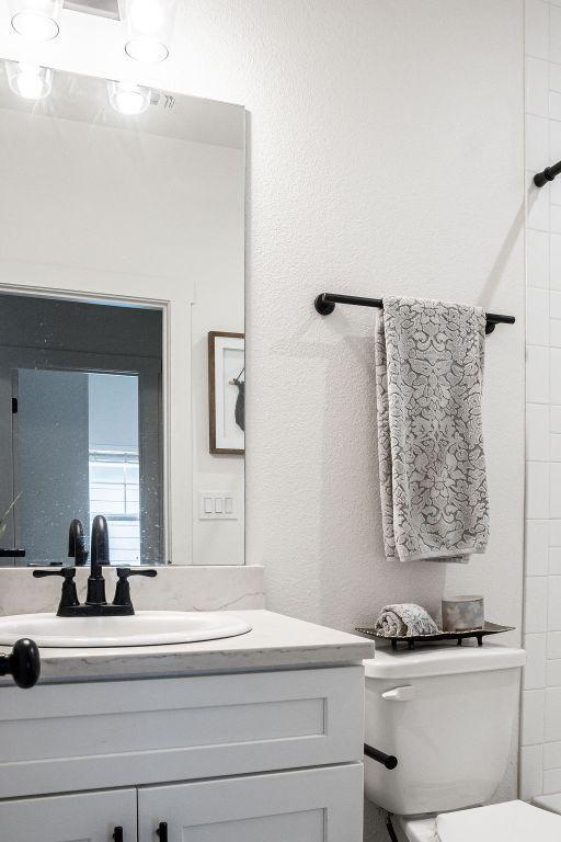 148 Feather Way, Fredericksburg, TX 78624 - bathroom featuring toilet, vanity, and a textured wall