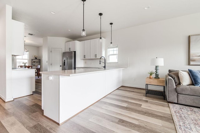 148 Feather Way, Fredericksburg, TX 78624 - kitchen with stainless steel fridge, open floor plan, a peninsula, light wood-type flooring, and light countertops