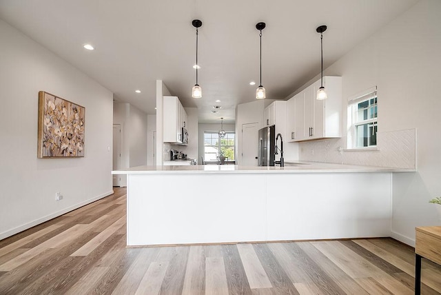 148 Feather Way, Fredericksburg, TX 78624 - kitchen featuring white cabinetry, light wood-style flooring, light countertops, appliances with stainless steel finishes, and tasteful backsplash