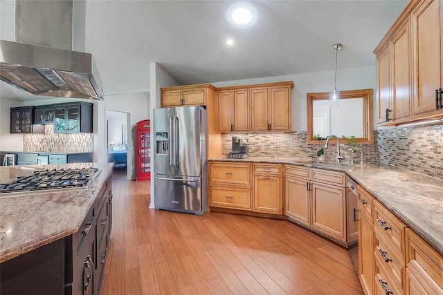 408 Sombrero, Horseshoe Bay, TX 78657 - kitchen with appliances with stainless steel finishes, wall chimney range hood, light stone counters, light wood-type flooring, and decorative backsplash