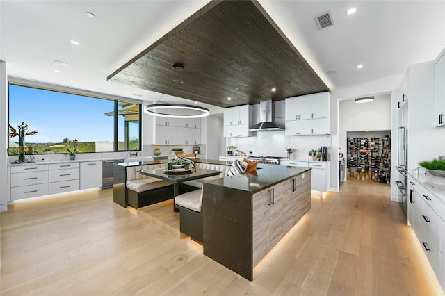 8209 Two Coves Dr, Austin, TX 78730 - kitchen with wall chimney range hood, a spacious island, modern cabinets, light wood-style floors, and recessed lighting