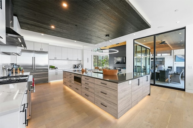 8209 Two Coves Dr, Austin, TX 78730 - kitchen with appliances with stainless steel finishes, light wood finished floors, modern cabinets, wall chimney range hood, and wood ceiling
