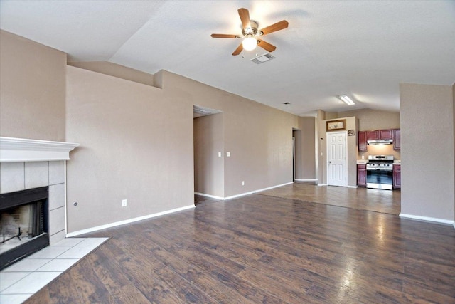 102 Cavalry Trl, Elgin, TX 78621 - unfurnished living room with vaulted ceiling, a ceiling fan, wood finished floors, a tile fireplace, and baseboards
