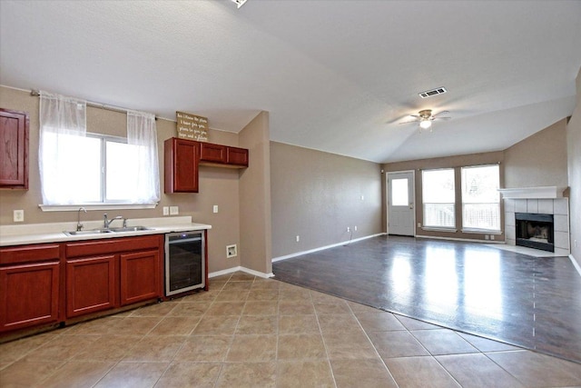 102 Cavalry Trl, Elgin, TX 78621 - kitchen featuring beverage cooler, ceiling fan, a tiled fireplace, light countertops, and lofted ceiling