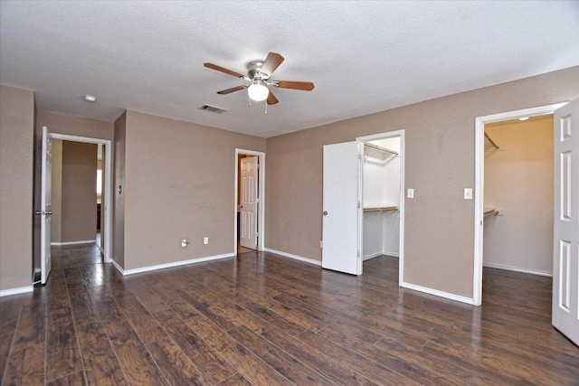 102 Cavalry Trl, Elgin, TX 78621 - unfurnished bedroom featuring a walk in closet, wood finished floors, a closet, and a textured ceiling