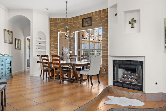 17308 Saint Therese Rd, Manor, TX 78653 - dining area with built in features, a chandelier, tile patterned floors, arched walkways, and a fireplace