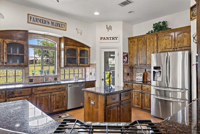 17308 Saint Therese Rd, Manor, TX 78653 - kitchen with appliances with stainless steel finishes, a sink, decorative backsplash, light tile patterned floors, and dark stone countertops