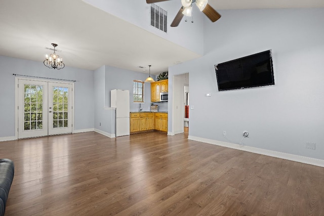 17308 Saint Therese Rd, Manor, TX 78653 - unfurnished living room featuring baseboards, dark wood-type flooring, a ceiling fan, a chandelier, and french doors
